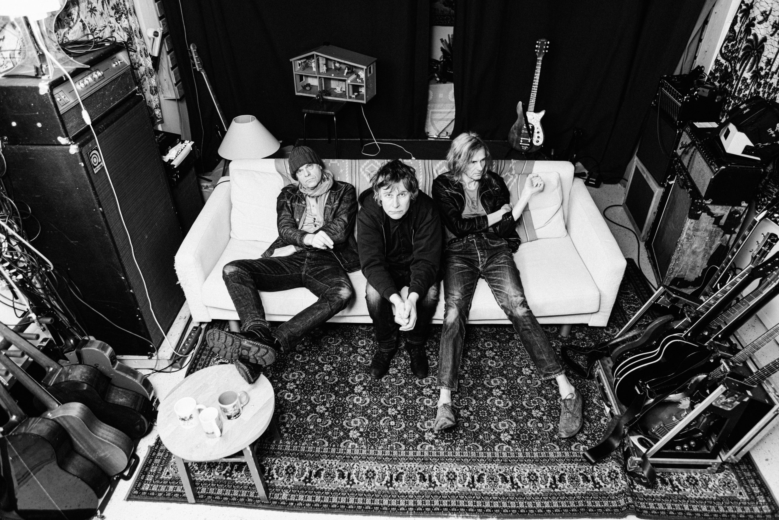 bändi istuu sohvalla mustavalkoisessa kuvassa.